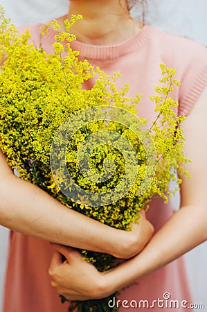 Young woman in a rosy dress holding a bunch of colorful picked w Stock Photo