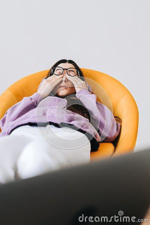 Young woman rubs her eyes after using glasses in front laptop. Eye pain or fatigue concept Stock Photo