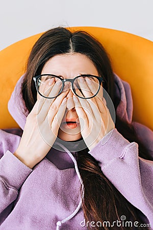 Young woman rubs her eyes after using glasses in front laptop. Eye pain or fatigue concept Stock Photo