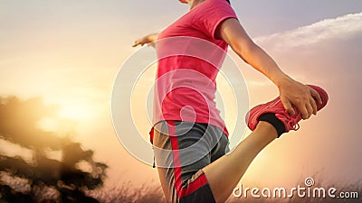 Young woman runner stretching legs before running in sunset rural Stock Photo