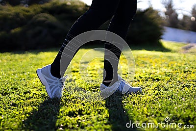 Young woman running on the field in the morning. Active person outdoor. Close-up on shoe Stock Photo