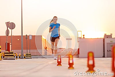 Young woman running on parking level in the city at sunset Stock Photo