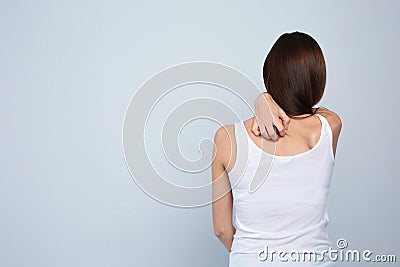 Young woman scratching back on light background Stock Photo