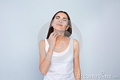 Young woman scratching neck on light background Stock Photo