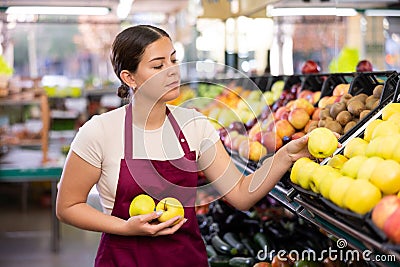 Young woman seller lays out apples in supermarket Stock Photo