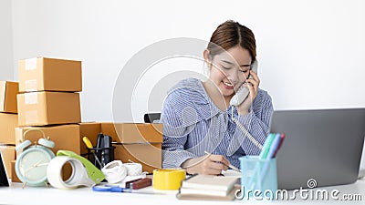 Young woman selling products online was talking on the phone to receive an order from a customer who called and wrote down the lis Stock Photo