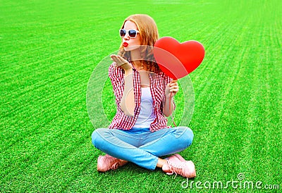Young woman sends an air kiss with red balloon in the shape of a heart Stock Photo