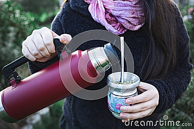 Young woman serving mate in a natural space. Latin beverage. Stock Photo