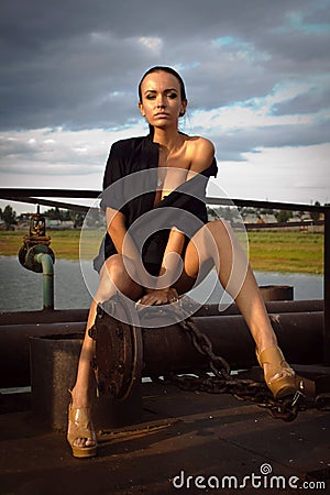 Young woman only in shirt, high heels, long legs. Metal structures, dramatic sky. fashion style Stock Photo