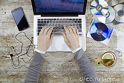 Young woman shooting from above working on laptop on wooden table listening to music cd with a cup of tea and headphone Stock Photo