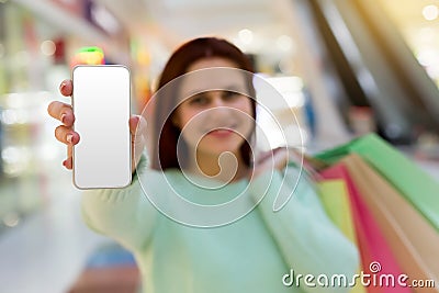 Young woman with shopping bags showing the phone`s screen directly to the camera Stock Photo