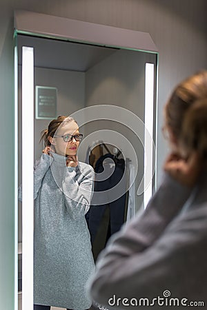 Young woman shopping in a fashion store, trying on some clothes she likes Stock Photo