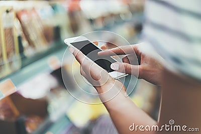 Young woman shopping healthy food in supermarket blur background. Close up view girl buy products using smartphone in store Stock Photo