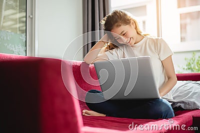 Young woman shopping online with internet in happy mood on red sofa. Business and working concept, Relax and part time concept Stock Photo