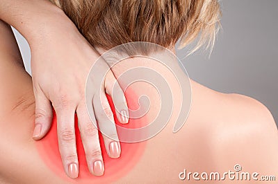 Young woman with shoulder pain, massaging her shoulder Stock Photo