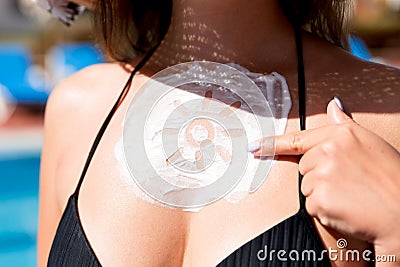 Young woman showing on sun cream in sun shape by the pool. Sun Protection Factor in vacation, concept Stock Photo