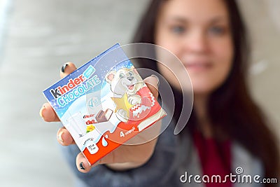 Young woman shows Kinder Chocolate Candy box in colored wrapping. Kinder chocolate by Italian Confectionery Manufacturer Ferrero Editorial Stock Photo