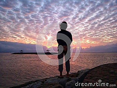 Young woman silhouette standing on beach looking at the dramatic sunrise sky view. Stock Photo