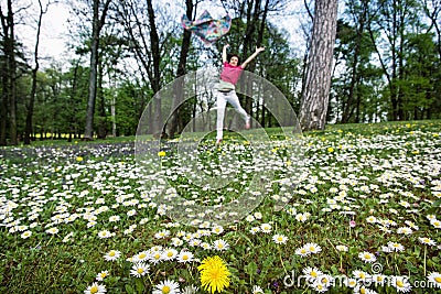 Young woman with silk scarf is jumping on the meadow full of ox-eye daisies and dandelions Stock Photo