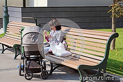 A young woman sits on a bench in the garden Editorial Stock Photo