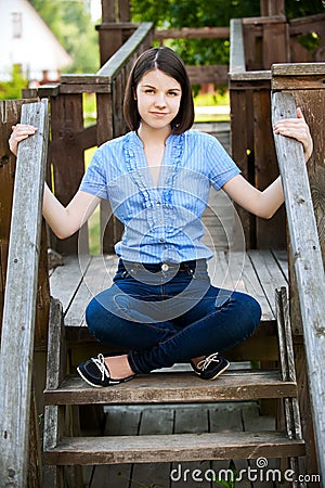 Young woman sits on wooden ladder Stock Photo