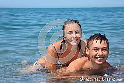 Young woman sitting astride man in sea near coast Stock Photo