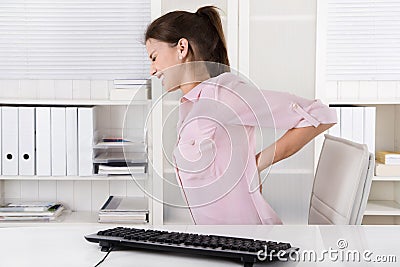 Young woman sitting with backache in the office. Stock Photo