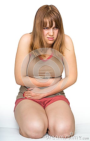 Young woman sitting on the bed with stomach pain Stock Photo