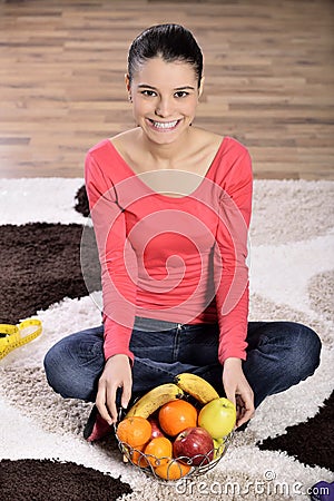 Young woman sitting on carpet and enjoying fruits Stock Photo