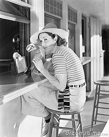 Young woman sitting at a counter drinking a coca cola Stock Photo