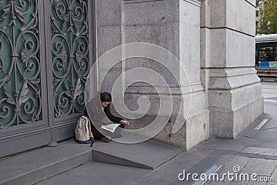 Woman sitting in the doorway of the Bank of Spain Editorial Stock Photo