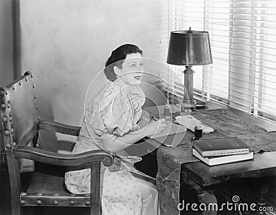 Young woman sitting at her desk writing a letter Stock Photo