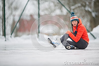 Young woman sitting on the ice rink after falling down Stock Photo