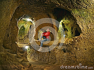 Young woman sitting on the rock .Derinkuyu cave underground city Stock Photo