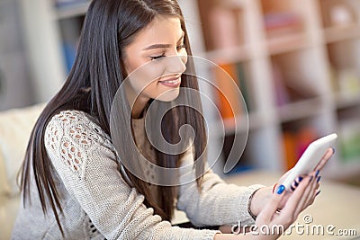 Young woman sitting on a sofa and send text messages Stock Photo