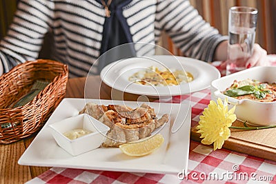 A young woman woman sitting at table with traditional Italian cuisine, lasagna, pumpkin soup with cheese and fried fish. Stock Photo