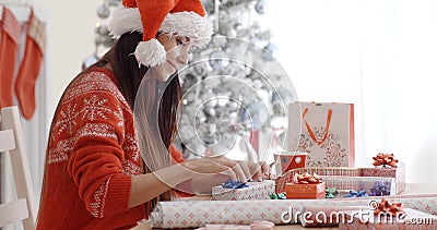 Young woman sitting wrapping Christmas gifts Stock Photo