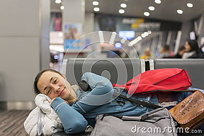 Young woman sleeping at the airport while waiting for her flight. Tired female traveler sleeping on the airpot departure gates Stock Photo