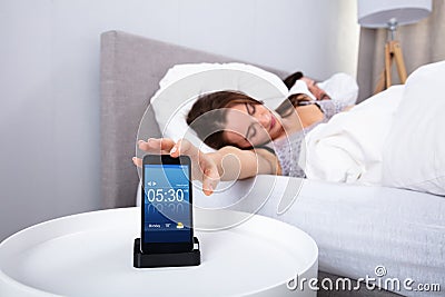 Woman sleeping near alarm set on mobile phone Stock Photo
