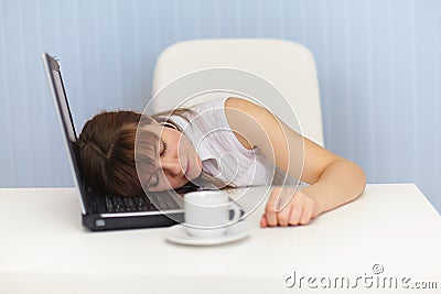 Young woman sleeps on laptop keyboard on workplace Stock Photo