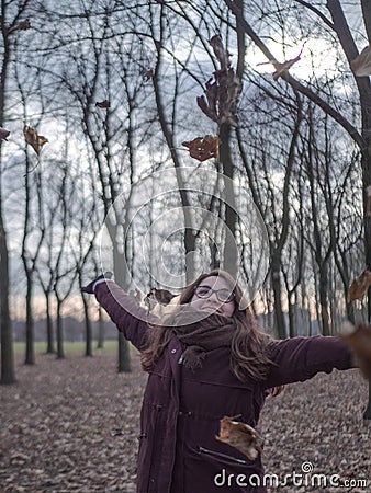 Young woman smiles in the middle of the forest while the leaves fall on her Stock Photo