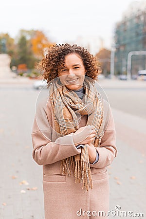 A young woman smiling at the camera dressed warm outside in city Stock Photo