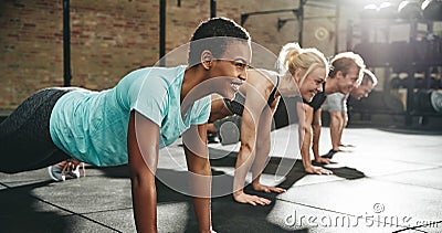 Young woman smiling while doing pushups in an exercise class Stock Photo