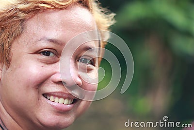 A young woman smiling to camera with green bokeh background. Stock Photo