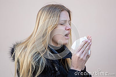 Woman sneezing in winter in black jacket Stock Photo
