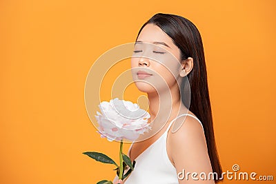 Young woman sniffing pink peony flower closed her eyes on yellow background Stock Photo