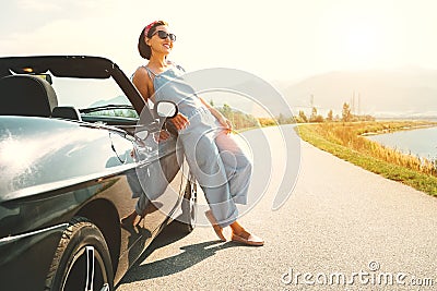 Young woman solo traveler stay near cabriolet car on picturesque Stock Photo