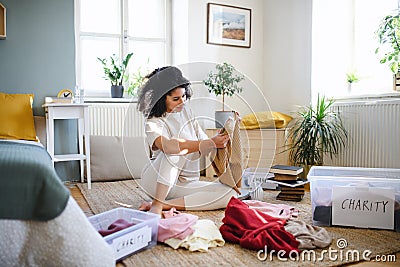 Young woman sorting wardrobe indoors at home, charity donation concept. Stock Photo