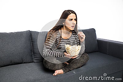 Young woman spends his free time watching TV on the couch munching chips and popcorn white background. Stock Photo