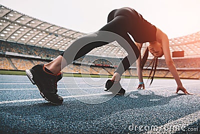 Young woman in sportswear in starting position on running track stadium Stock Photo